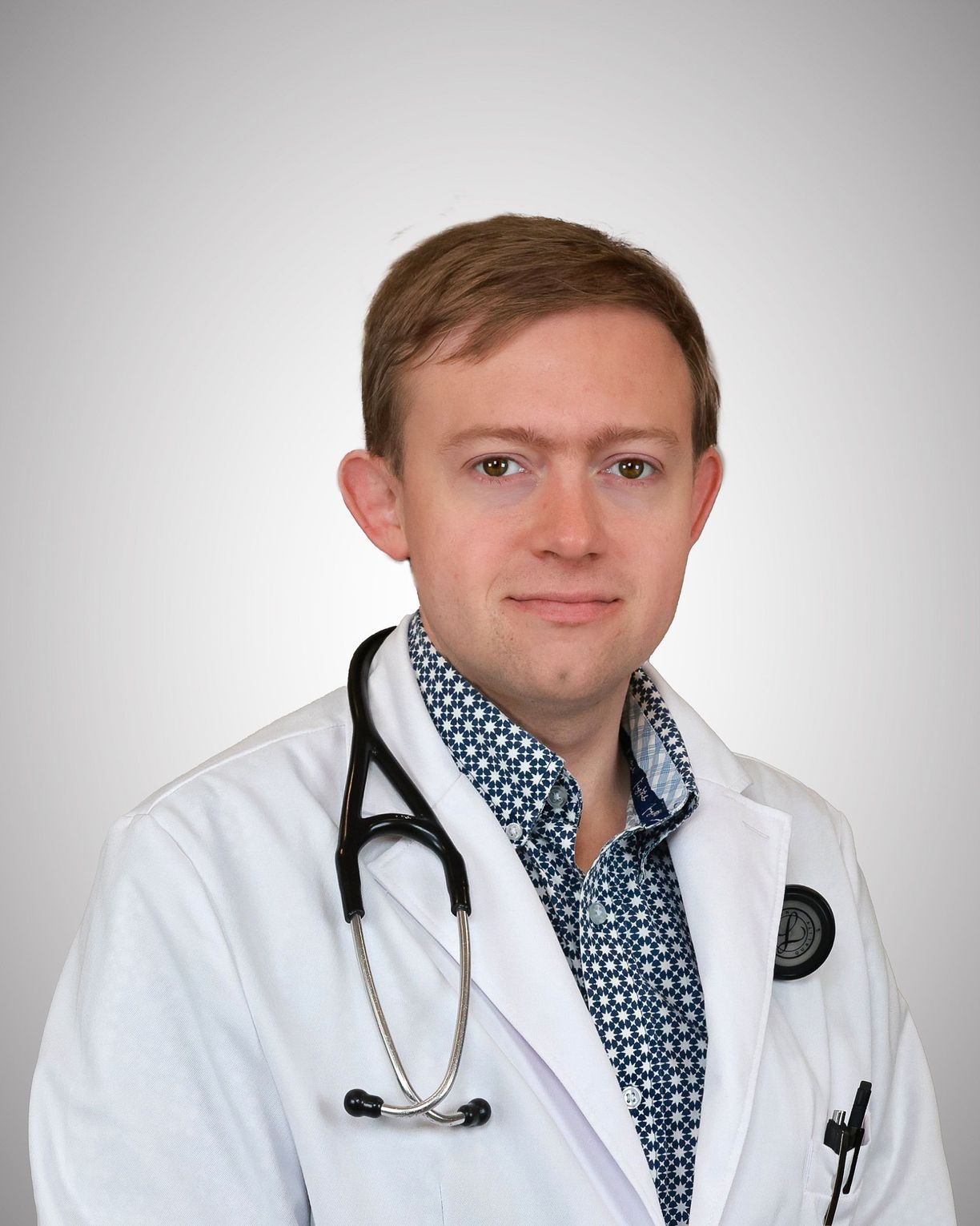 Portrait of William Hoskinson, DO, in a white coat with a stethoscope